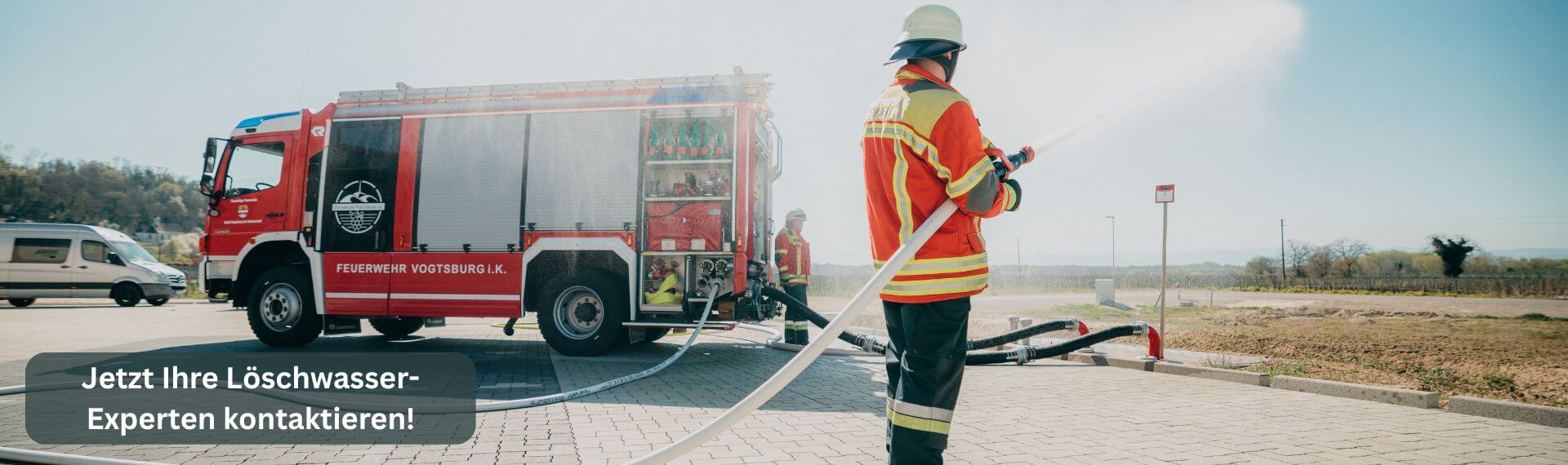 Feuerwehrmann steht vor dem Feuerwehrauto und setzt das Löschwasser aus dem Löschwassertank ein