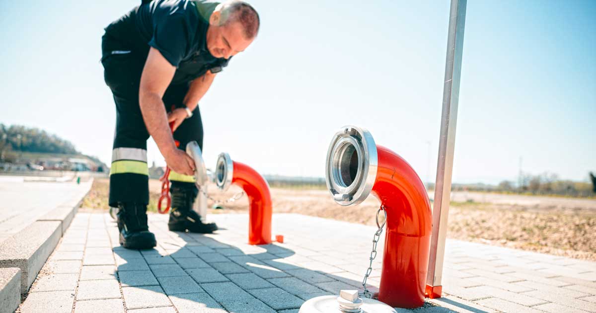 Löschwasserbervorratung-Feuerwehr Feuerwehrmann benutzt die Löschwassersaugstelle im Rahmen der Löschwasserbevorratung